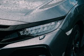 Close-up of a rain-covered car bonnet and LED headlight